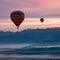 Spectacular dawn/dusk scene with hot air balloons above mist covered valleys and colorful mountain backdrop