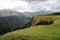 Spectacular green mountain landscape on sunny day with mountain peaks covered by clouds and green sunny hills