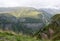 Spectacular green mountain landscape on sunny day with snow mountain peaks covered by clouds