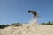 Spectacular jumping belgian shepherd catching its toy in sand dunes on a sunny day with clear sky