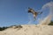 Spectacular jumping belgian shepherd catching its toy in sand dunes on a sunny day with clear sky