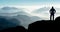 Spectacular layered mountain ranges with valley fog. Man Silhouette reaching summit enjoying freedom.