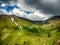 Spectacular mountain landscape with clouds hovering above mountain slopes filled with bushes of rhododendron kotschyi in fagaras m