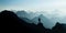 Spectacular mountain ranges silhouettes. Man reaching summit enjoying freedom.