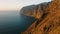 Spectacular ocean view with warm sunset light at Los Gagantes cliffs enormous crags. Flight along high volcanic rocky