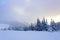 Spectacular panorama is opened on mountains, trees covered with white snow, lawn and blue sky with clouds.