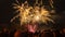 Spectacular view of a crowd watching beautiful fireworks explode in a smoky sky at night