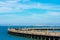 Spectacular view of weathered Municipal Pier opened for fishing and strolling. Background naval ship painted gray is passing in