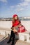 Spectacular woman in knee high boots sitting with map on white bench. Outdoor portrait of lovely female tourist posing