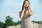 Spectacular young woman in a light long dress stands on the beach and touches her face with her hands