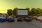 Spectators at a car parking lot with cars, an inflatable screen