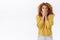 Speechless, concerned and shocked pretty redhead curly woman in yellow sweater, gasping, hold hands on mouth and stare