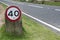 Speed limit sign on grass verge by side of road