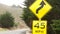 Speed limit yellow sign, curves, turns or winding road. California, Big Sur, USA