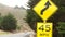 Speed limit yellow sign, curves, turns or winding road. California, Big Sur, USA