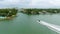 Speedboat heading towards water channel in Miami Beach. Green area with houses and villas with private berths for yachts