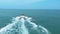 the speedboat is moving towards the horizon at high speed, making waves at sea