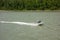 A speedboat traveling upriver against a strong current in the springtime