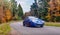 Speeding car blurred arred road through colorful autumn trees