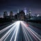 Speeding cars blur against illuminated city skyline backdrop