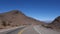 Speeding down the winding and empty asphalt road in the middle of the desert, between mountains. POV shot