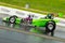 Speeding green dragster on a drag strip