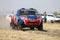 Speeding red and blue Toyota Nissan single cab rally car front v