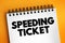 Speeding ticket - a ticket issued for driving above the speed limit, text concept on notepad