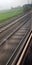 Speeding train tracks, trails of rain with meadows in the background