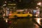 Speeding yellow taxi drives down rainy wet New York road at night with lights, New York