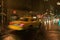 Speeding yellow taxi drives down rainy wet New York road at night with lights, New York