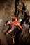 Speleologist descend by the rope in the deep vertical cave tunnel. Cave man hanging over abyss.