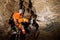 Speleologist descend by the rope in the deep vertical cave tunnel. Cave man hanging over abyss.