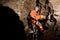 Speleologist descend by the rope in the deep vertical cave tunnel. Cave man hanging over abyss.