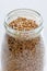 Spelt grains neatly stored in a glass jar against a clean white background, illustrating food storage