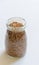 Spelt grains neatly stored in a glass jar against a clean white background, illustrating food storage