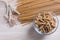 Spelt pasta with ears and spoon with grain on wooden table. Top view.