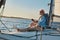 Spending some time alone. Side view of a relaxed senior man sitting on the side of sailboat or yacht deck floating in