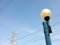 sphere white glass lamp on blue grunge steel light post under blurry high voltage pole and transmission power lines with clear sky