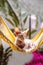 A Sphinx Cat on a Lies on a Fabric Hammock on a Tropical Background. AI