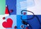 Sphygmomanometer bulb, stethoscope, disposable mask, paper heart, santa hat and baubles against the geometric background