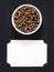 Spice allspice powder in white ceramic bowl and inscription plate on black wooden background, copy space