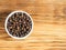 Spice allspice in white bowl on brown wood background with copy space