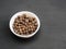 Spice allspice in white ceramic bowl on black wooden background. Healthy eating concept