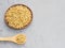 Spice coriander Coriandrum sativum seeds in clay plate and wooden spoon on gray concrete background