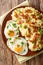 Spiced mashed potatoes with bacon and parsley served with fried eggs close-up on a plate. Vertical top view