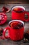 Spiced Pomegranate Apple Cider Mulled Wine Sangria in red mugs on wooden background.