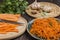 Spices, garlic and parsley on table. Raw chopped carrots and knife on cutting board. Fermented carrots in plate