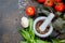 Spices in a stone mortar, green basil and tomatoes