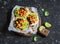 Spicy bean tostadas with corn salsa and avocado on a rustic cutting board on a dark background.